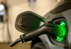 EV charger in a garage. The background is blurred and there is a green light. It is plugged into a vehicle.